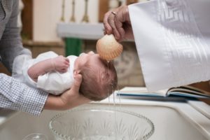 baby having water from a shell trickled over its head