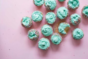 lots of blue iced cup cakes with rainbow sprinkles
