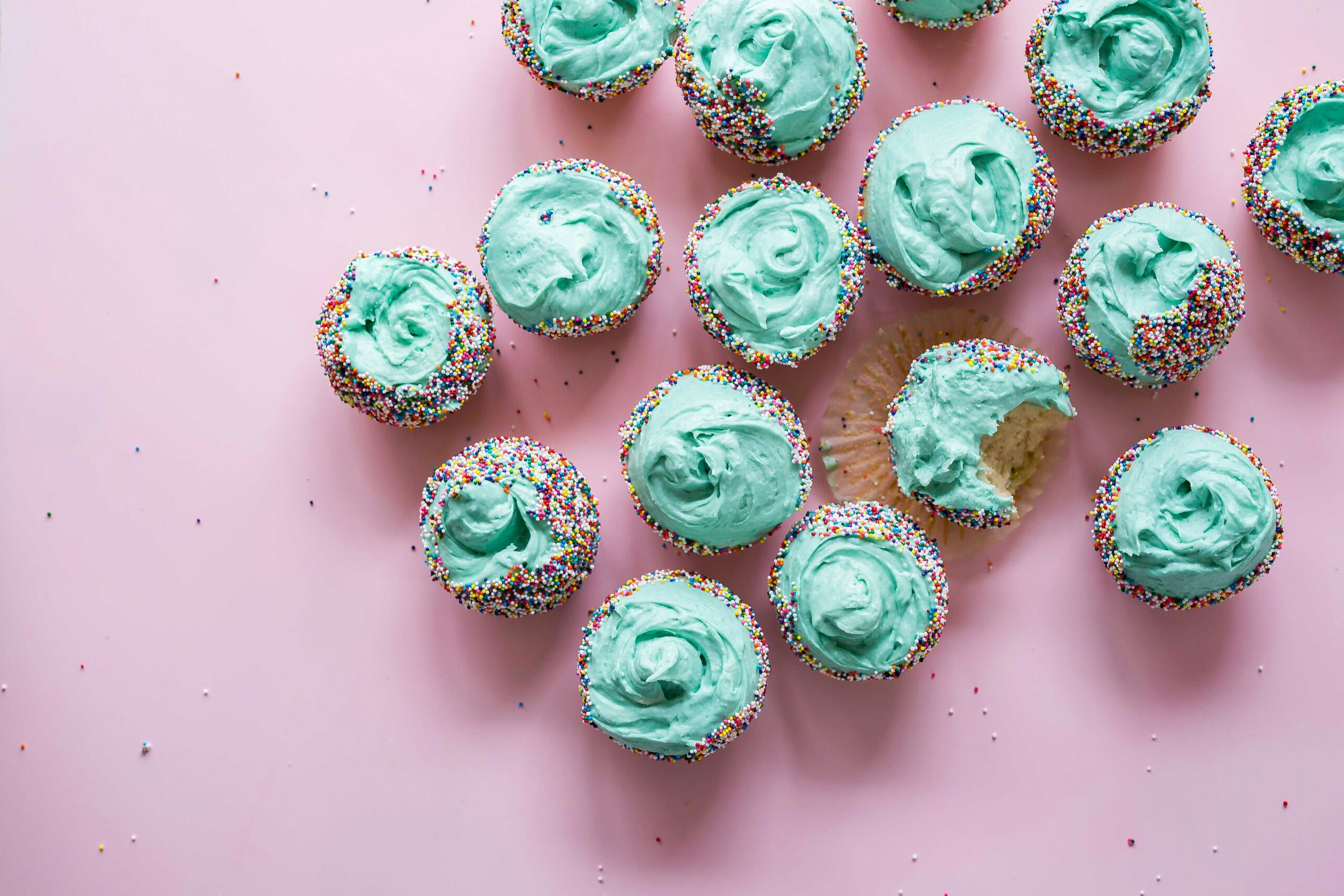 lots of blue iced cup cakes with rainbow sprinkles