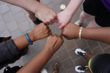 a diverse group of people giving a fist bump in a circle