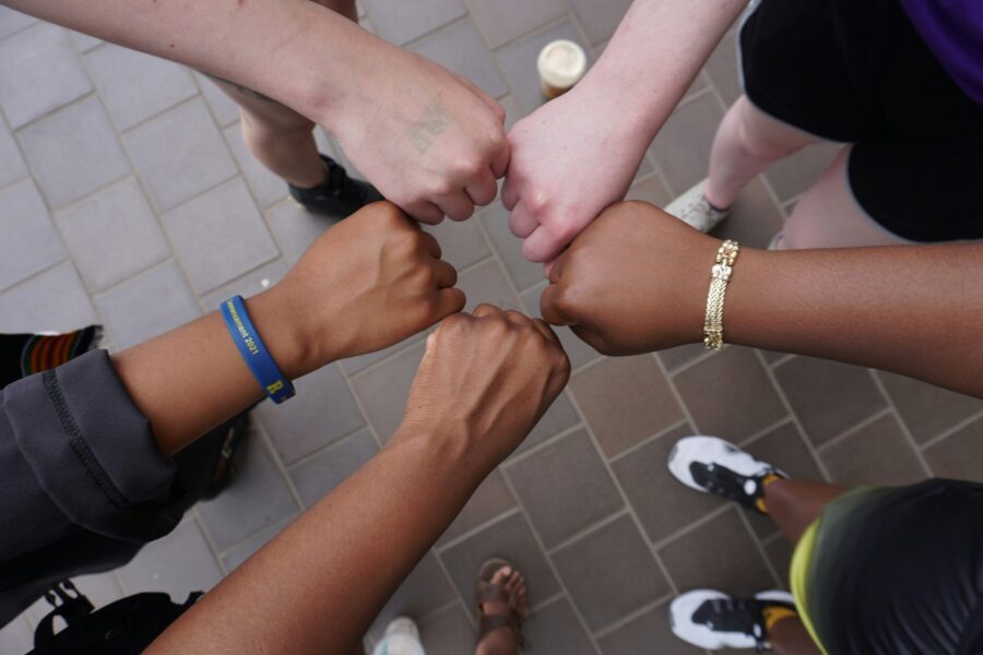 a diverse group of people giving a fist bump in a circle