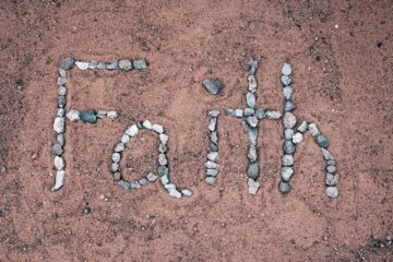 faith spelled out in stones on a beach
