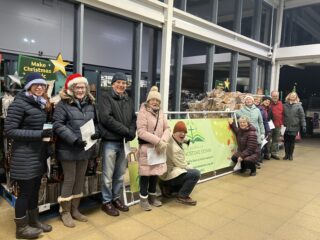 a group of POBD people singing outside Sainsbury's shop