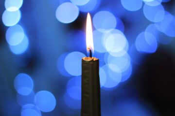A single candle against a blue flecked background