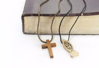 A bible with a cross and Jesus fish necklaces