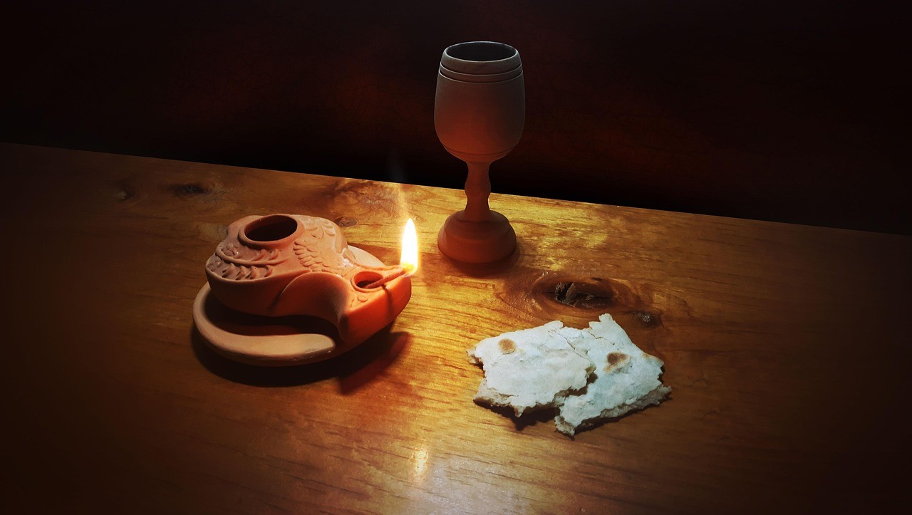 Image of broken bread wine and a lit oil lamp