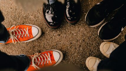 a group of people standing in a circle, showing just their shoes